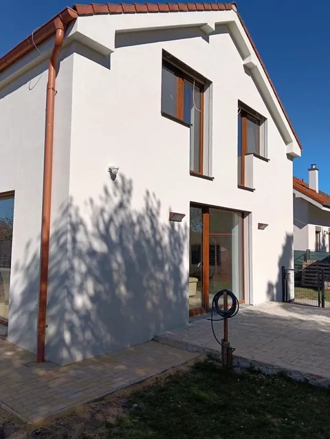 Hotová biela fasáda rodinného domu s drevenými oknami